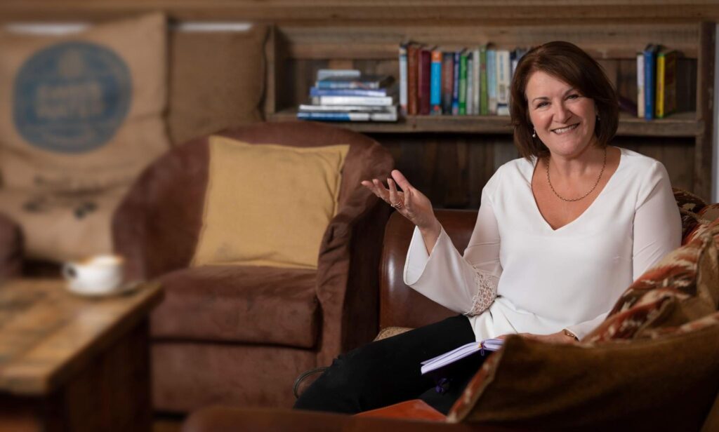 Louise Jenner sitting on a sofa with a book.