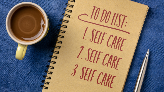 Coffee and a note book. On the cover it says: TO DO LIST 1. SELF CARE 2. SELF CARE 3. SELF CARE